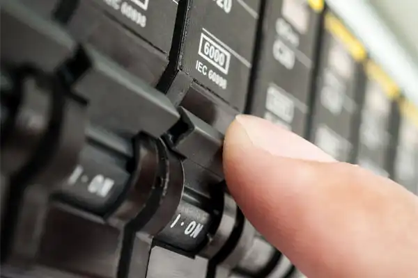 A finger switching an electrical circuit breaker to the "ON" position.