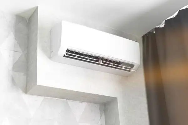 Wall-mounted air conditioner unit installed near a corner above a curtain.