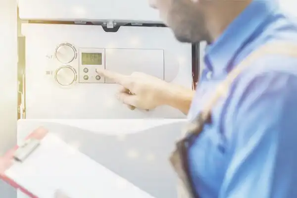 Person in blue shirt adjusting controls on a machine while holding a clipboard.