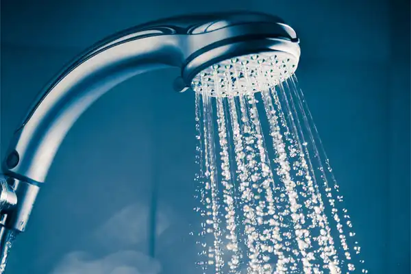 Showerhead with multiple water streams flowing, against a blue background.