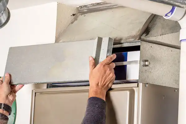 Person removing the panel of an HVAC system for maintenance inside a building.